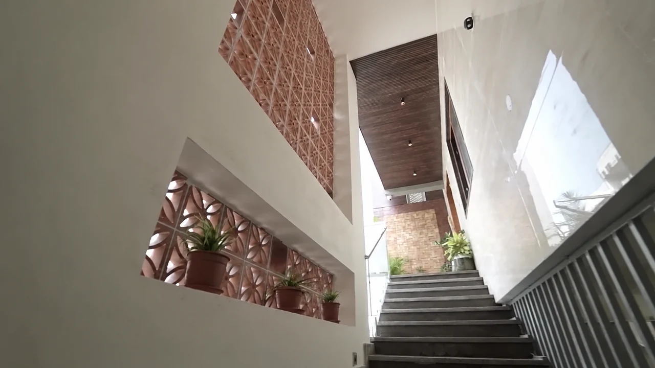 A stairwell ascending alongside a patterned brick screen and plants
